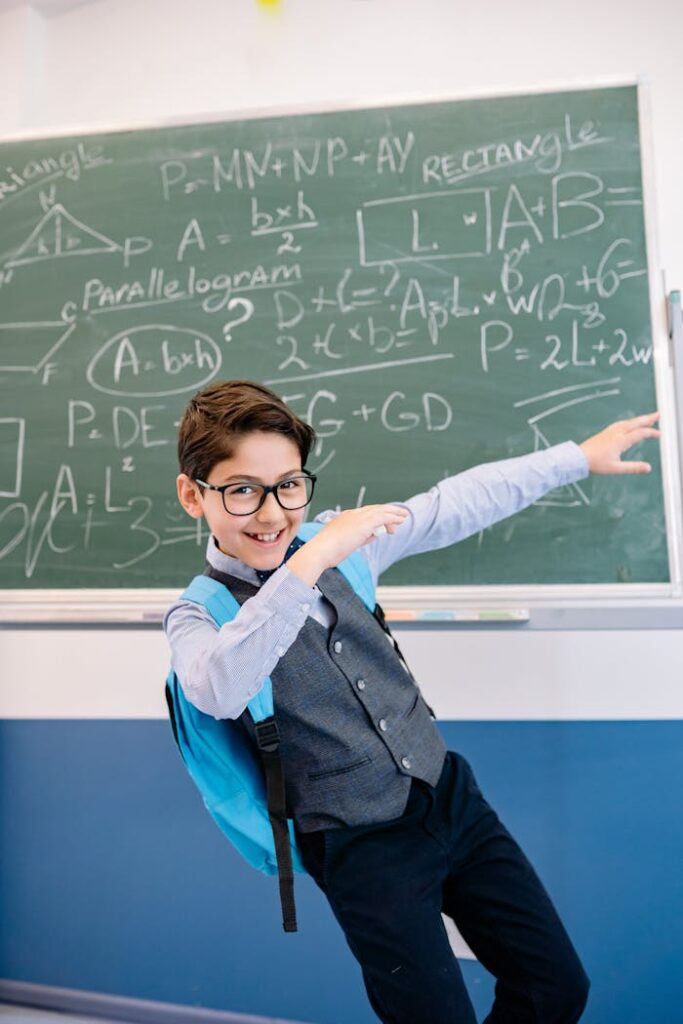 A Young Boy in Gray Vest Smiling and Posing in the Classroom